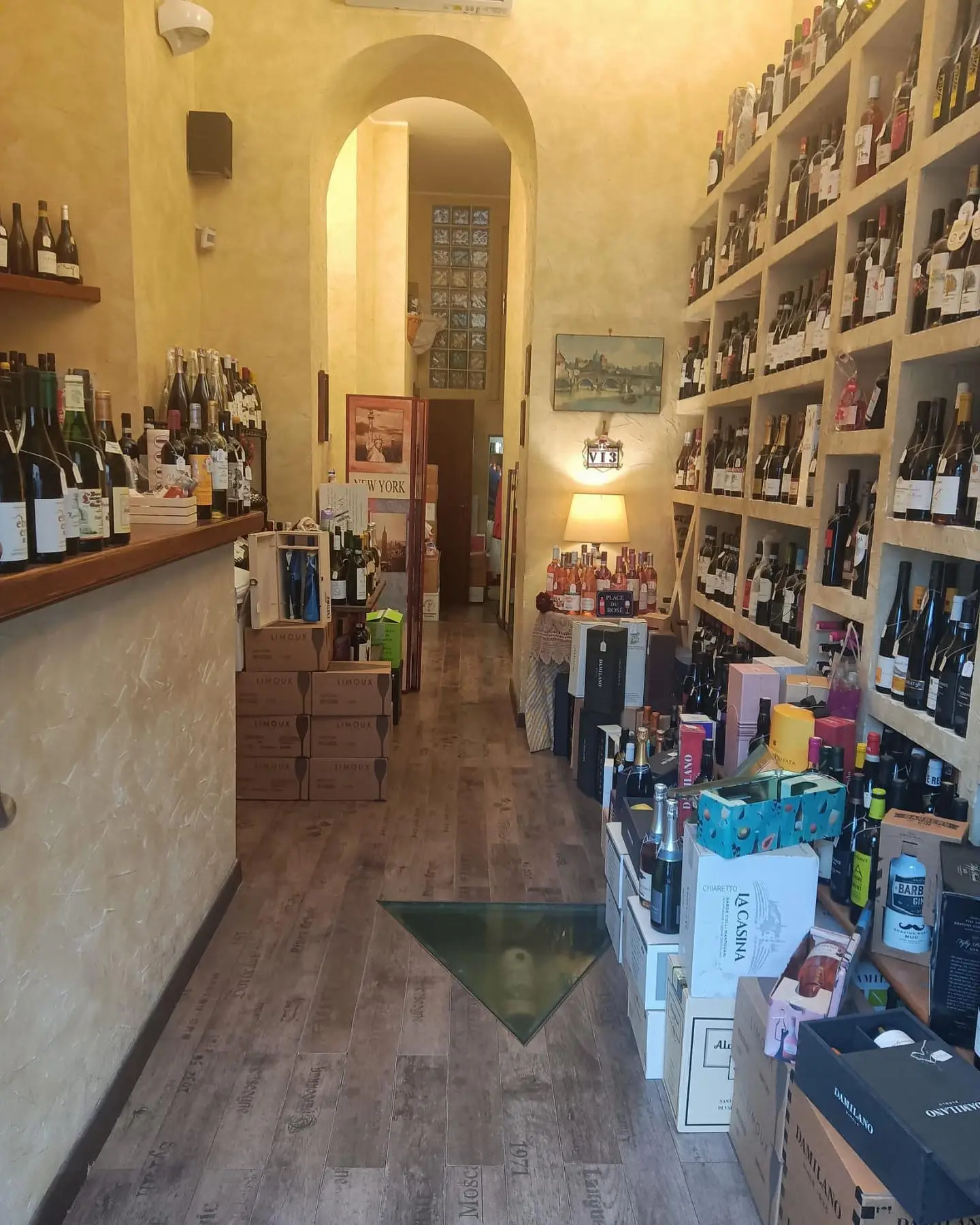 L’interno dell’enoteca: il corridoio tra gli scaffali di bottiglie e le casse di vino