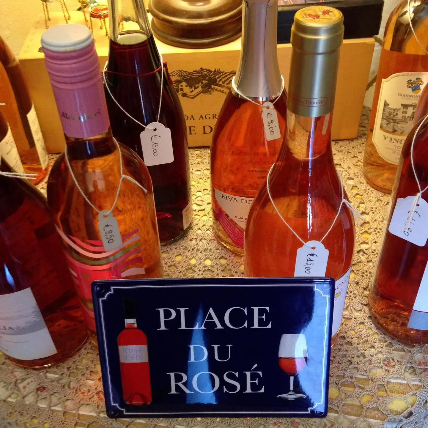 La targa smaltata Place du Rosé davanti a una fila di bottiglie di rosato