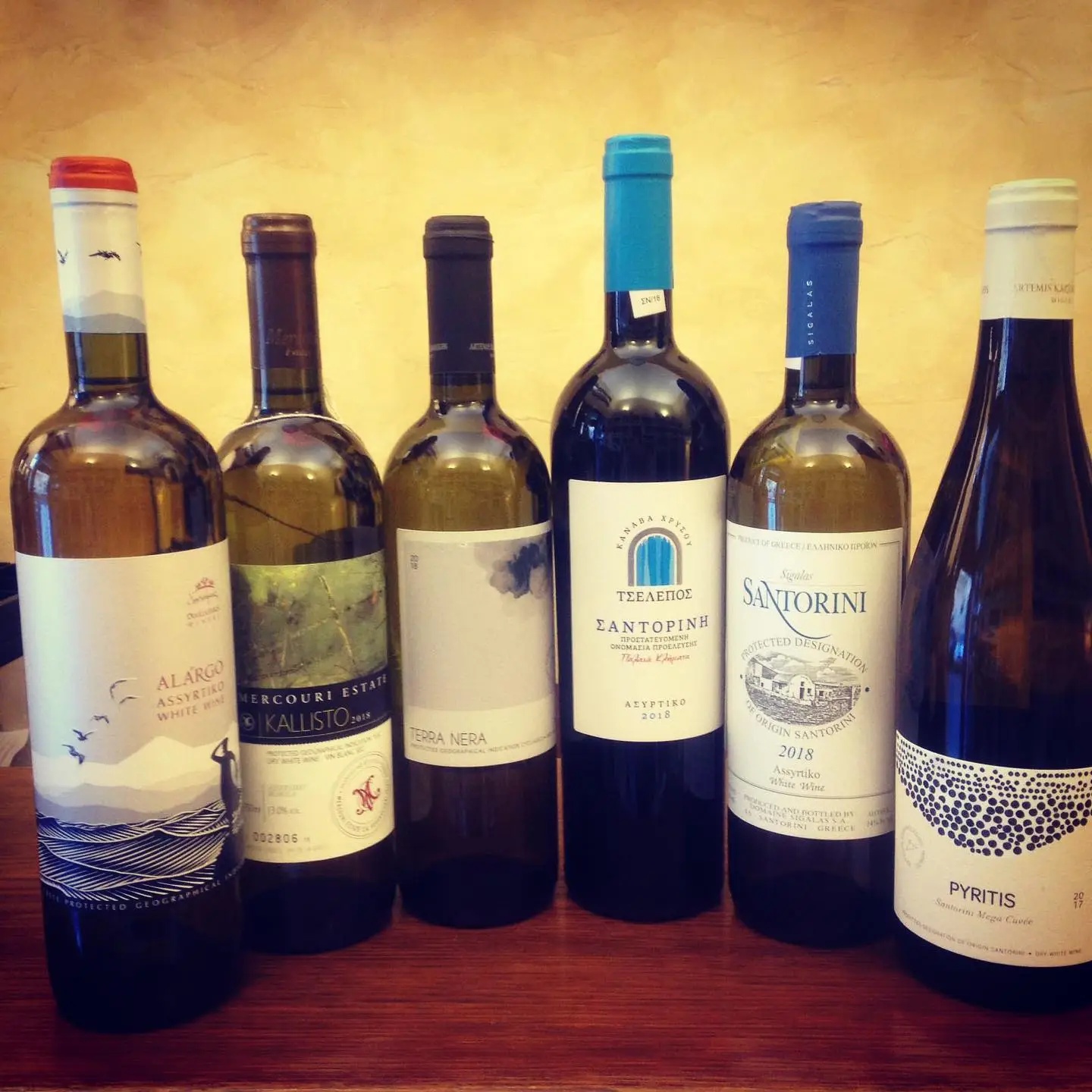 Sei bottiglie di vino bianco greco, tra cui un Santorini, sul bancone